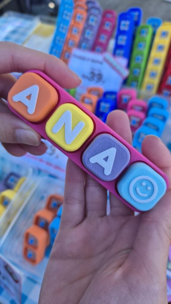 Mão segurando um fidget toy Piclick de 4 teclas com o nome ANA